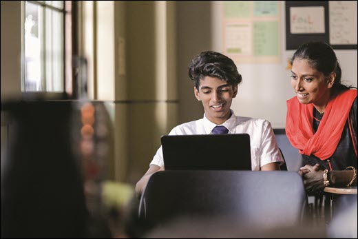 A photo of a teacher and a student looking at a computer.