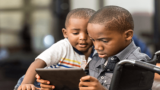 African American boy playing on tablet with his younger brother